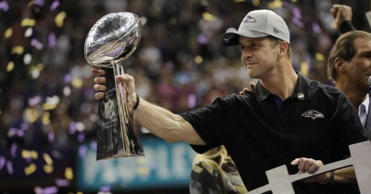 John Harbaugh holds a Super Bowl trophy after a Ravens win.
