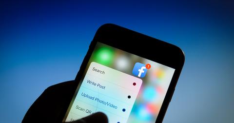 Una persona sosteniendo un teléfono con la aplicación de Facebook abierta.
