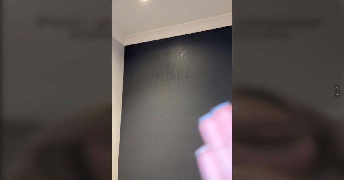 A woman shows the condensation on the bathroom walls