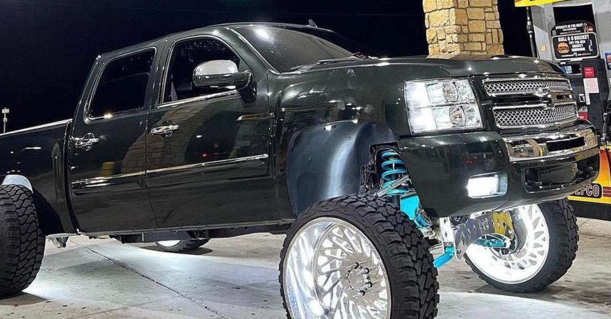 A black squatted truck parked at a gas station