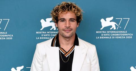 Christopher Abbott posing for a press photo in a white suit