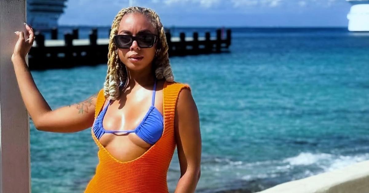 Mickey Lee stands in front of water with a cruise ship in it.