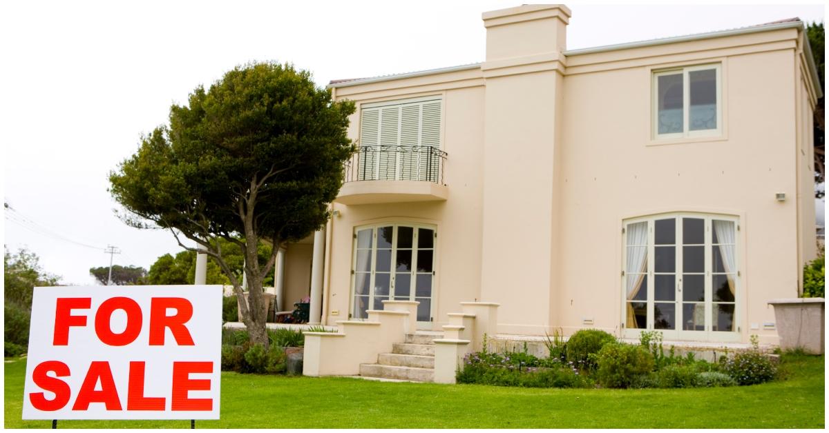 A house with a for sale sign in the front yard