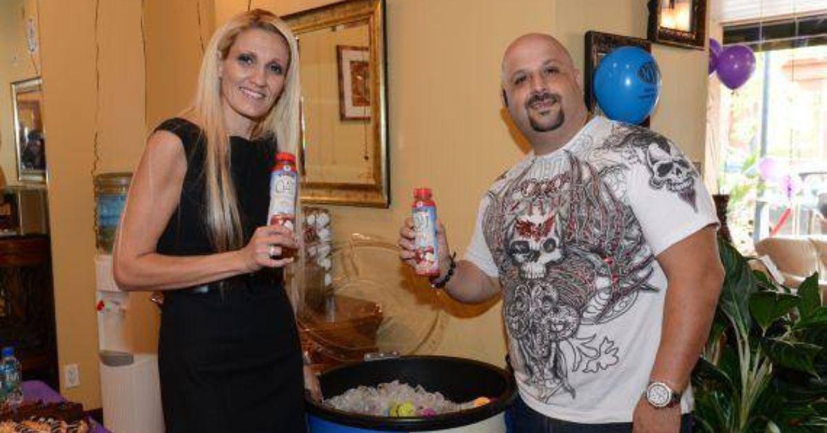 Penny Dossos-Karagiogis and Johnny Karagiogis pose for photos holding bottled beverages