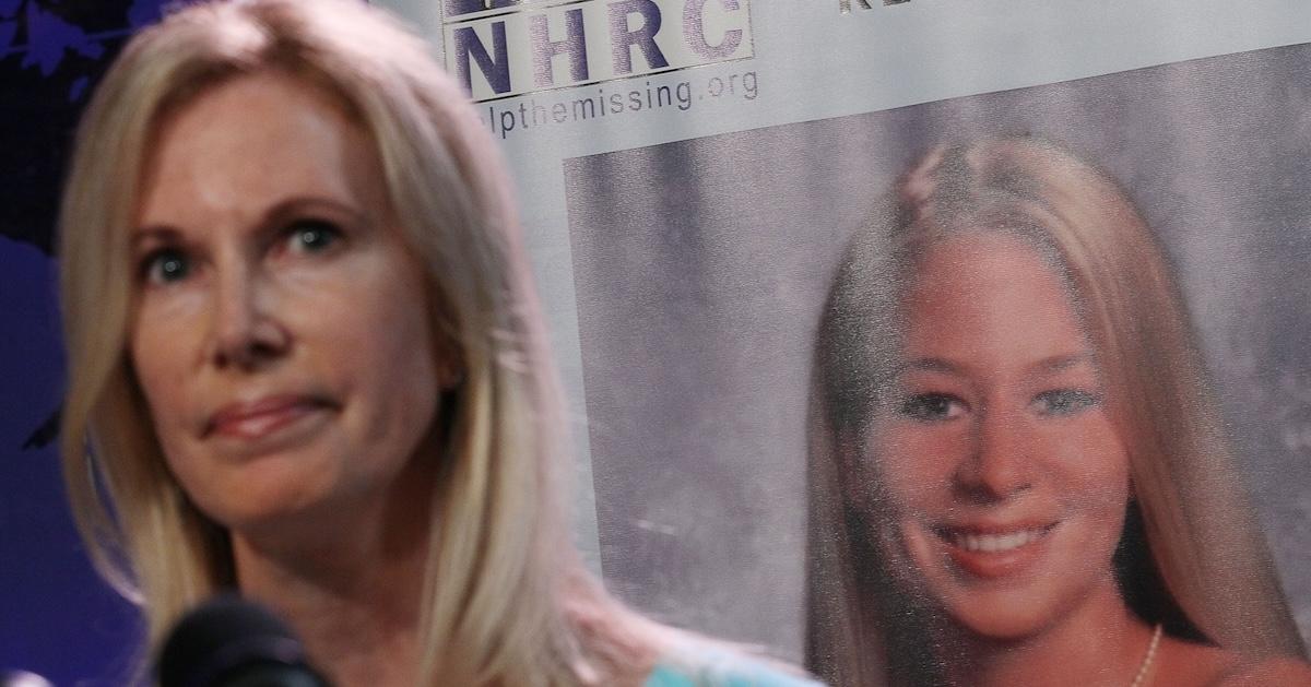 Beth Holloway standing next to a poster of Natalee Holloway