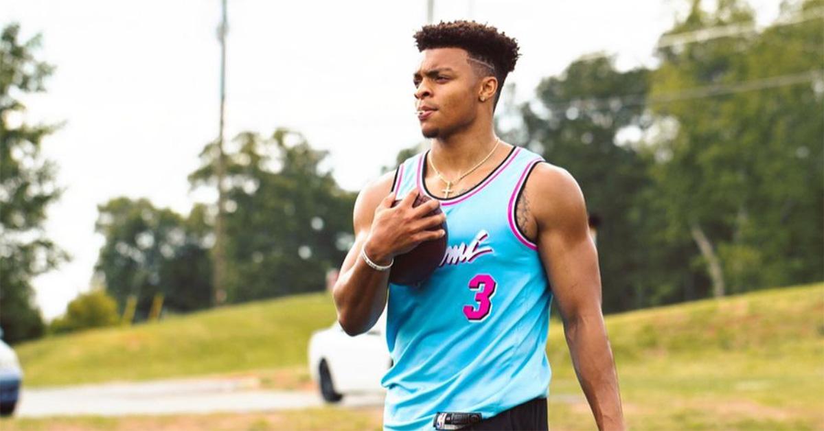 Justin Fields holding a football with a jersey on. 