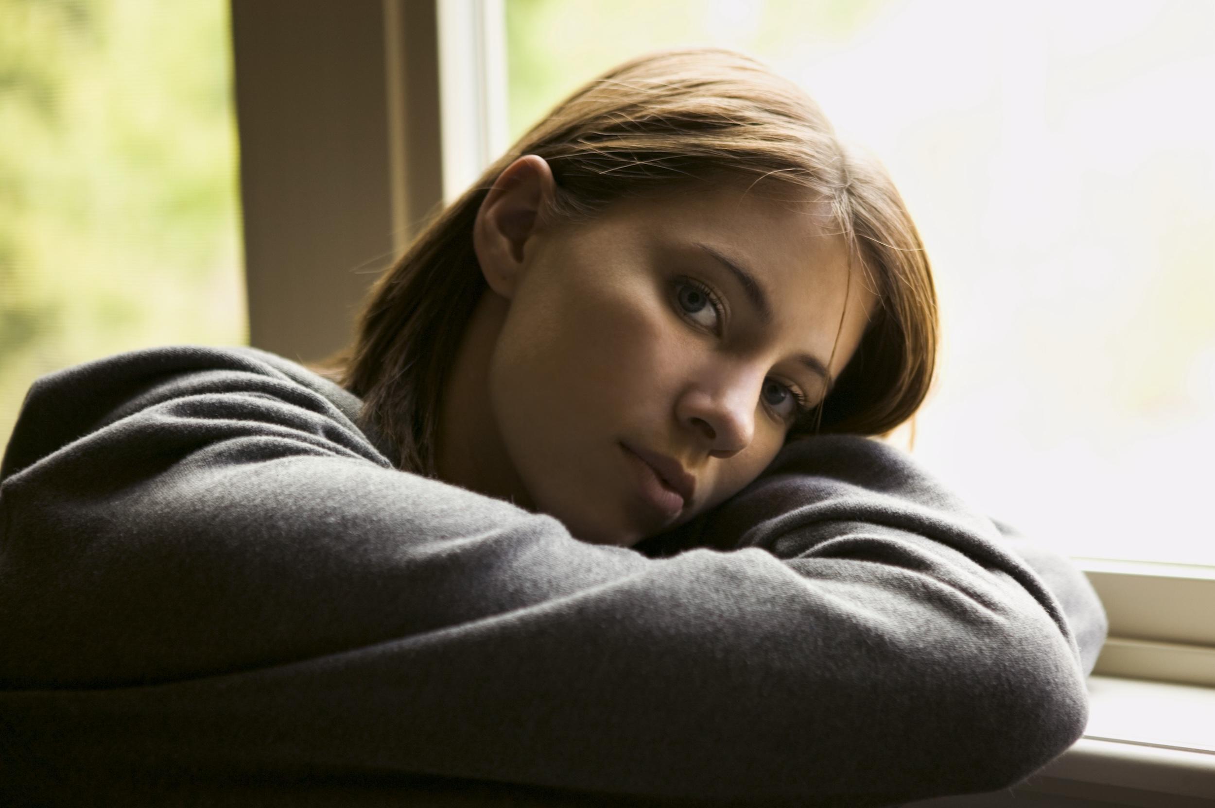 Portrait of a young woman leaning against a window ledge