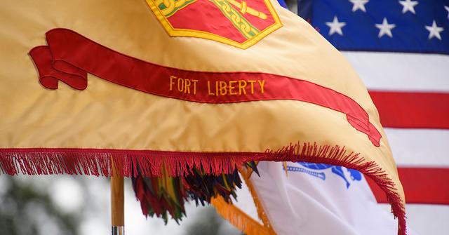 A flag that says Fort Liberty on it flowing in the wind.