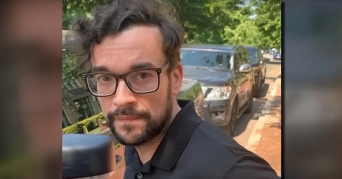 Eugene Gligor stands on the street in front of parked cars