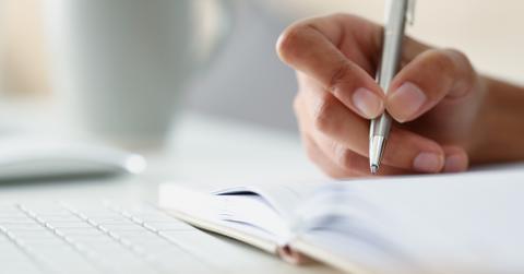 Writer making notes in a notepad.