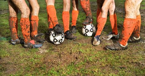 Soccer players show off their muddied and damaged socks on the field