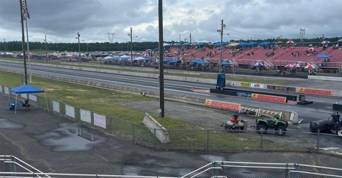 Altco Dragway on a cloudy day with people sitting in the stands under umbrellas.