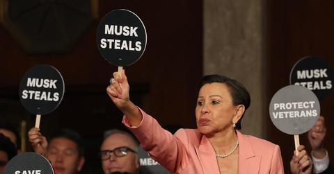 House Democrats hold up signs during President Donald Trump's Congressional address, one sign reading "Musk Steals"