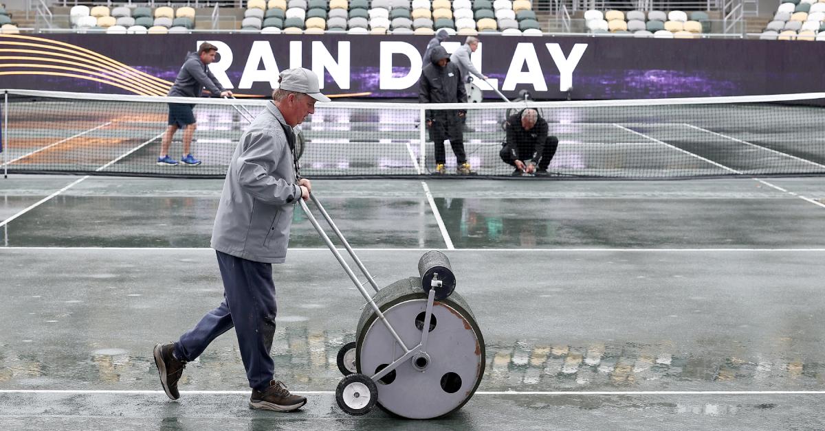 A ground crew works on drying a tennis court in 2024