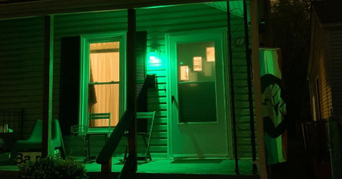 A green porch light on at a home.