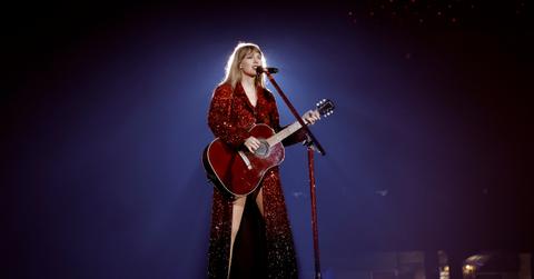 Taylor Swift on her Eras Tour wearing a red dress with red guitar