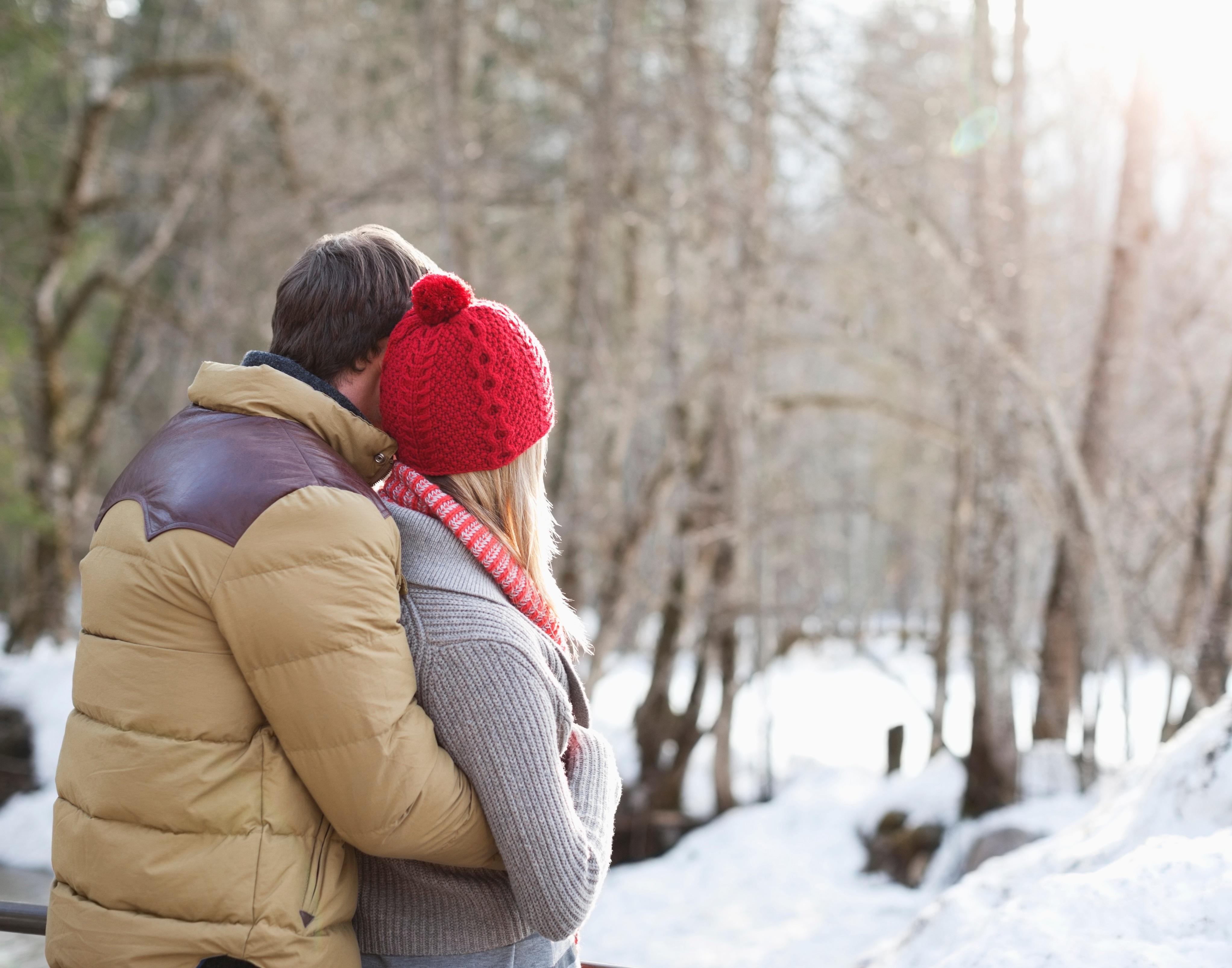 A couple hugs and snuggles together in the snow.