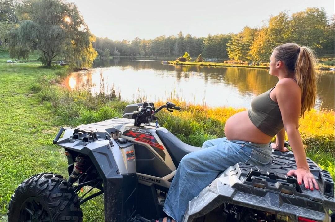 Nina sitting on an ATV with her baby bump