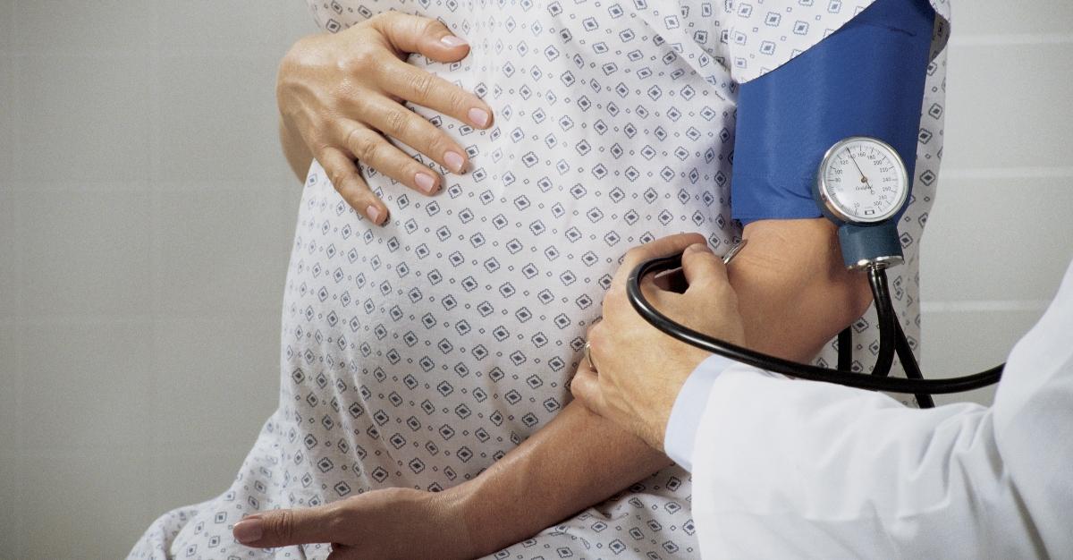 Doctor taking blood pressure from pregnant woman - stock photo