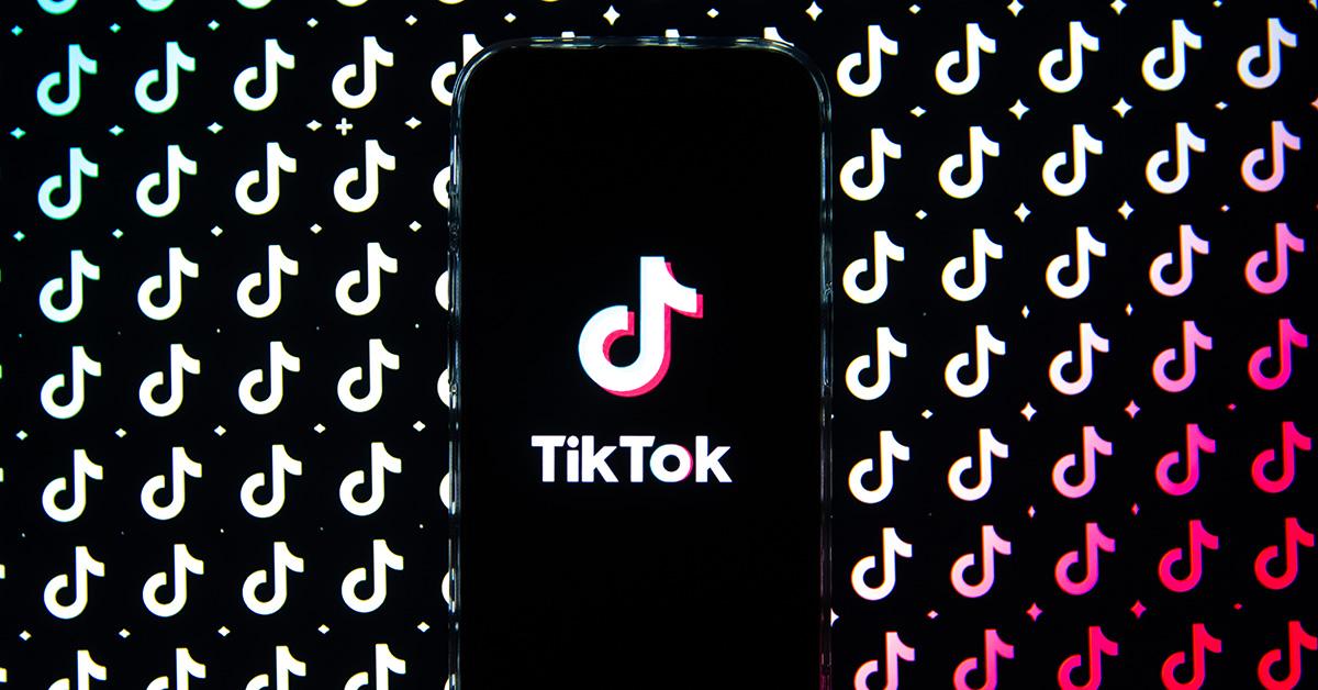 A TikTok logo on a phone screen with TikTok logos behind it. 