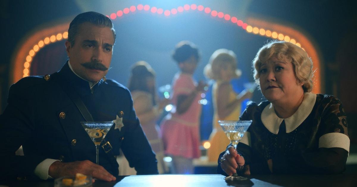 Jaime Camil as Sergeant Rivera and Ann Harada as Madam Frau having a drink at the bar in 'Schmigadoon'.