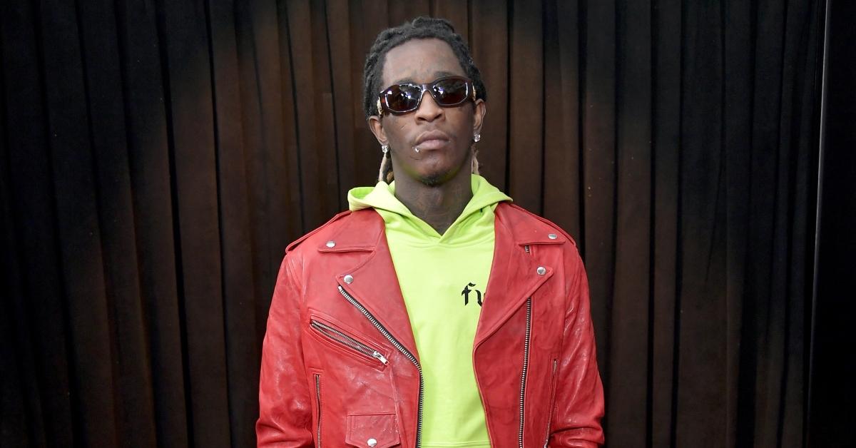 Young Thug with a neon green hoodie, a red jacket, and sunglasses on. 