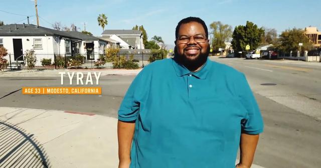 Tyray from '90 Day Fiance: Before the 90 Days' wears a blue shirt and smiles on the sidewalk.