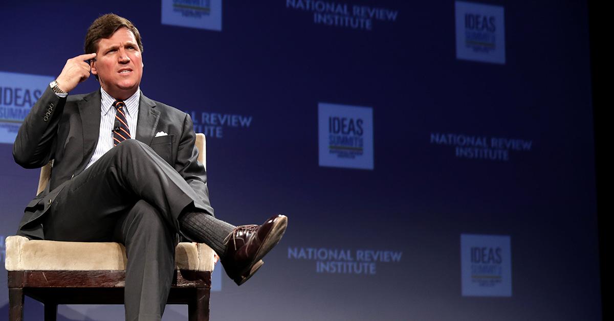 Tucker Carlson points at his head during the 2019 National Review Institute's Ideas Summit. 