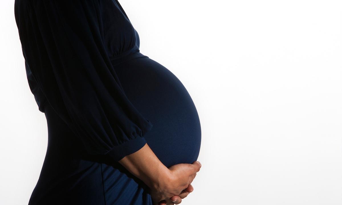 A pregnant woman cradling her baby bump