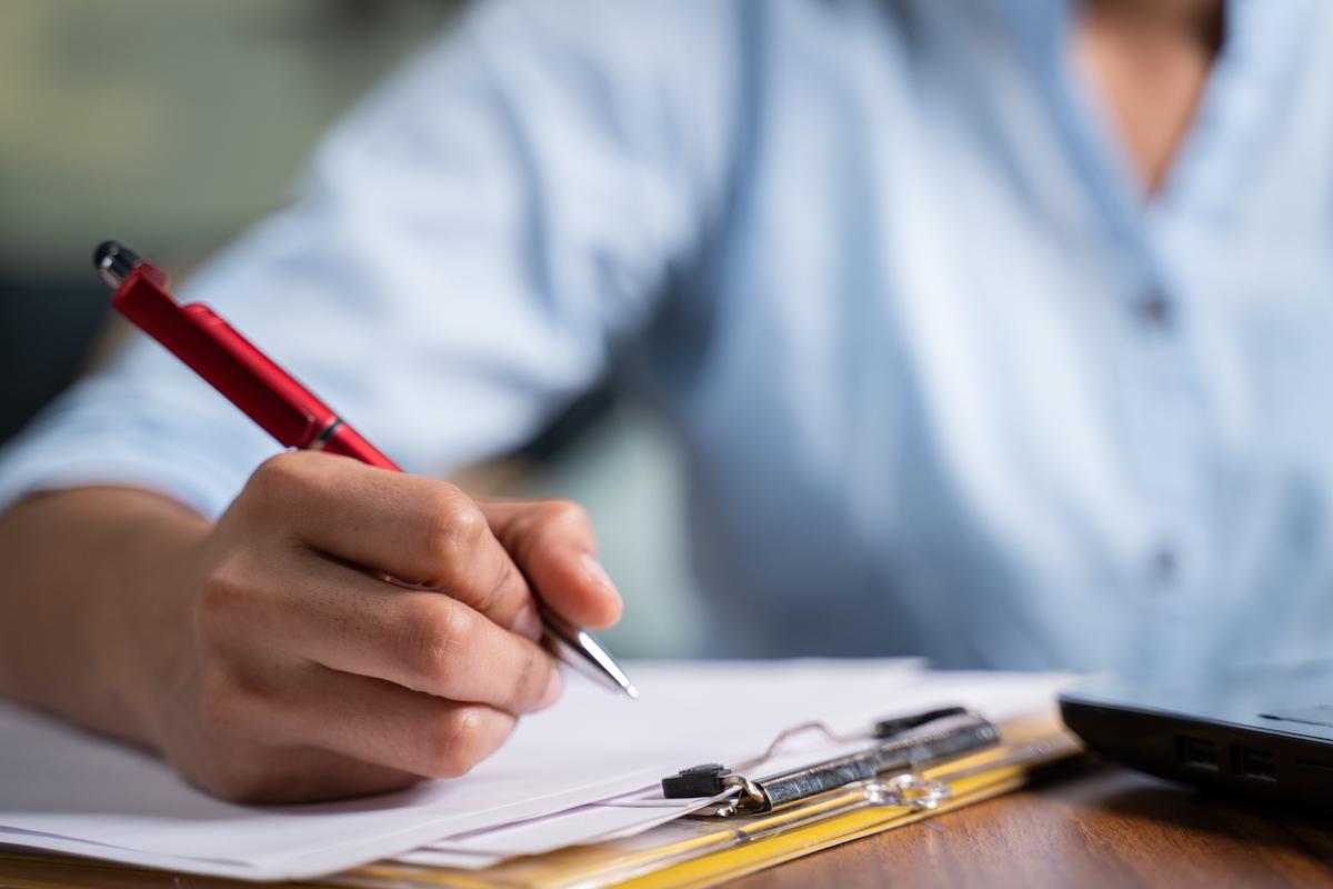 Woman holding pen to a paper on a clipboard.