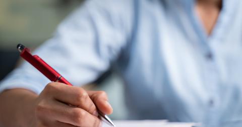 Woman holding pen to a paper on a clipboard.