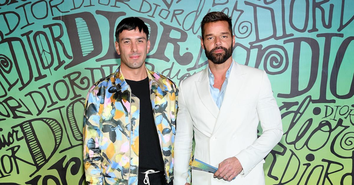 Ricky Martin wearing white jacket and Jwan Yosef wearing colorful jacket in front of Dior wall