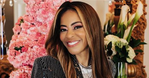 Mary Cosby in a black suit in front of a bunch of flowers