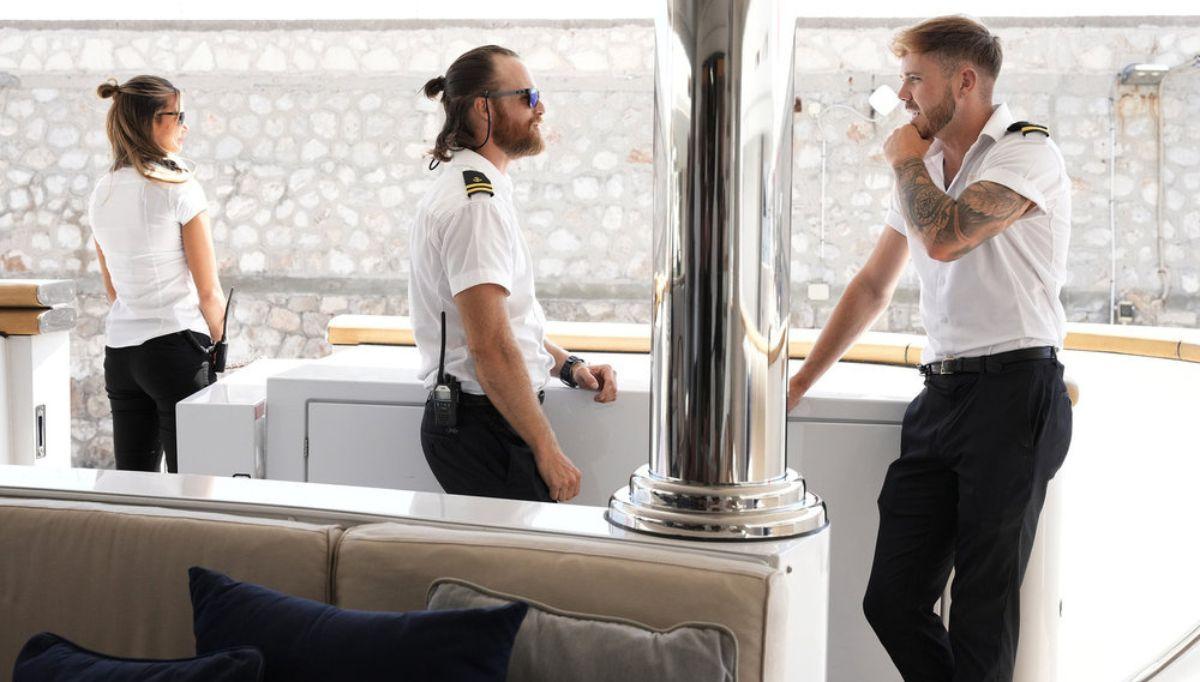 Gael Cameron stands in the background as Iain Maclean and Nathan Gallagher speak to each other on 'Below Deck Med'