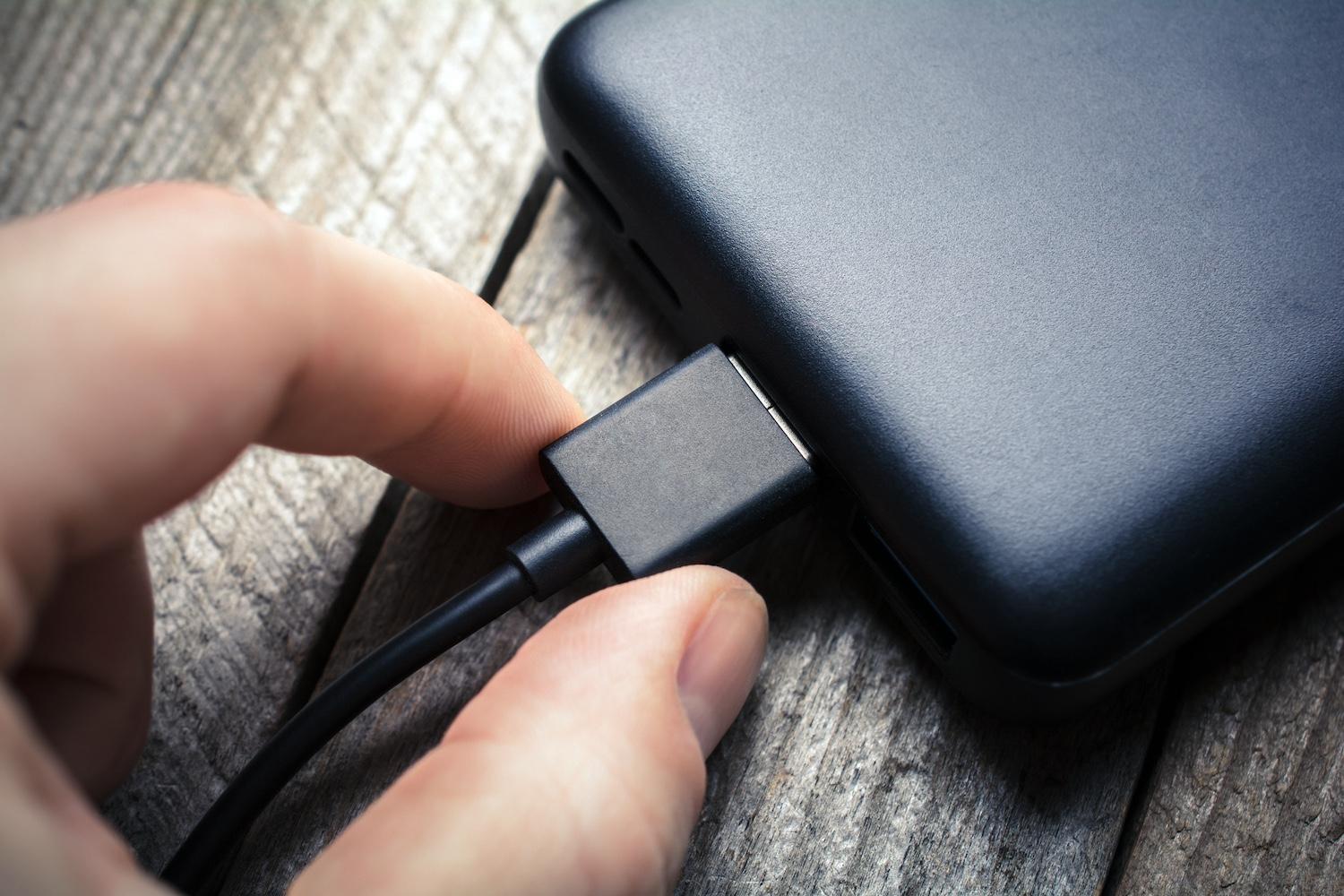 A person holding the plug for an external hard drive