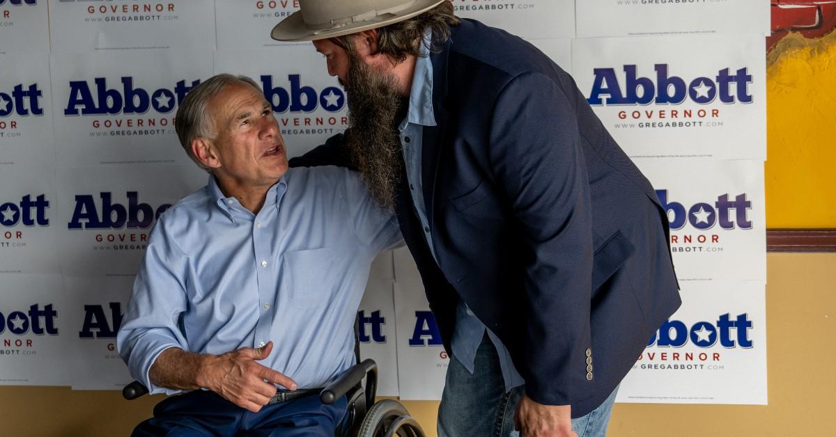 Greg Abbott talking with a man at a political rally. 