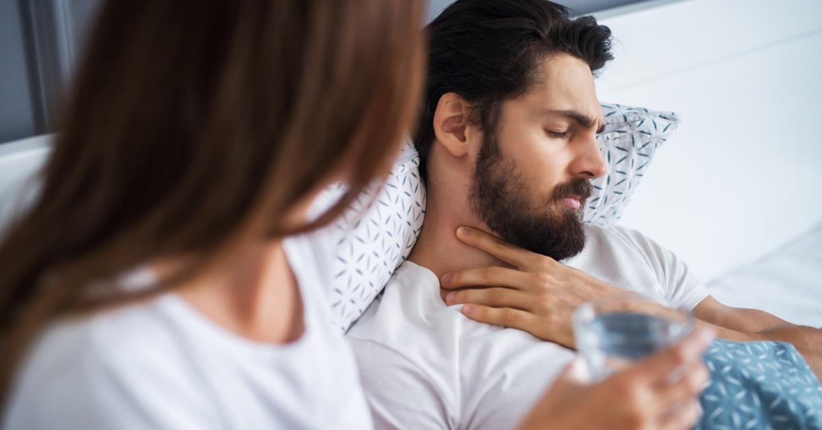 close up of attractive handsome bearded man having throat pain and picture id