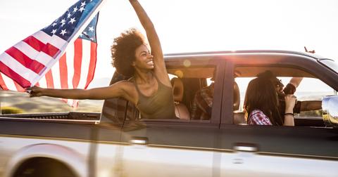 woman holding american flag outside car window