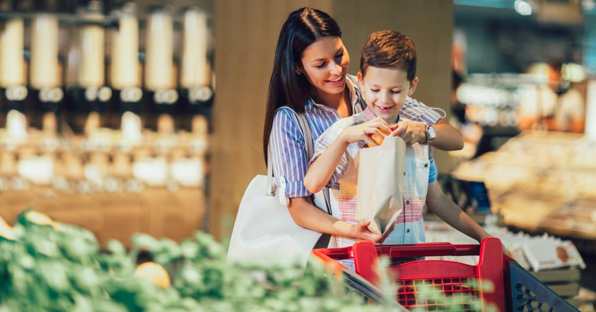 Mother and son buying fruit at grocery store or supermarket 