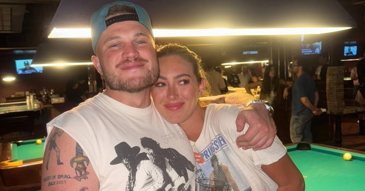 Zach Bryan with his wife in front of a pool table.