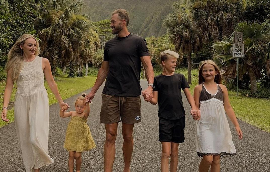 Munday family photo in Hawaii with Camille and Sam Munday hold hands with their three children in Hawaii