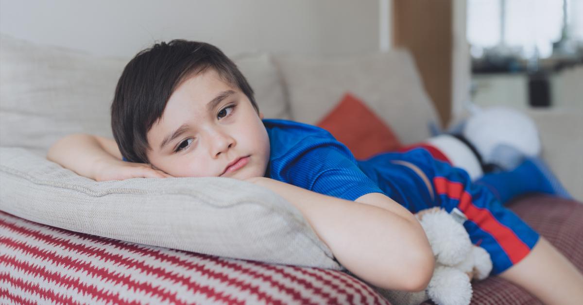 A lonely kid lying on a couch.