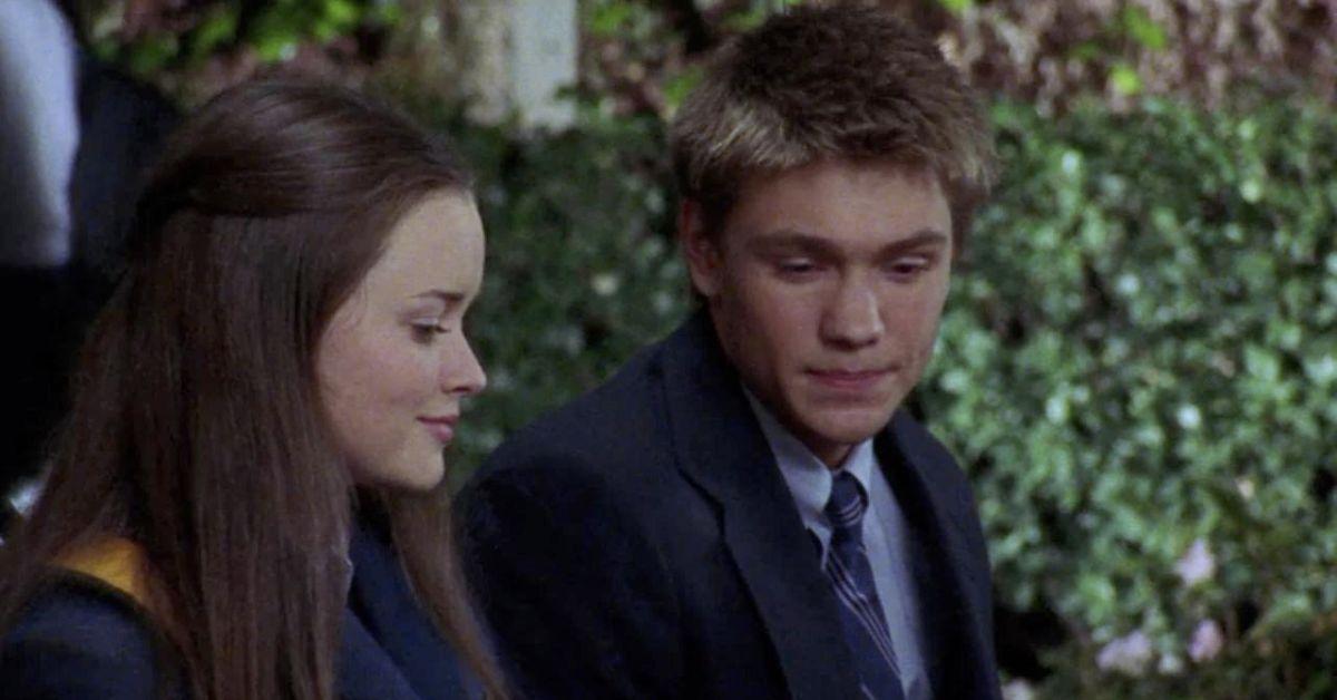 Tristan and Rory in 'Gilmore Girls' sit next to each other on a park bench